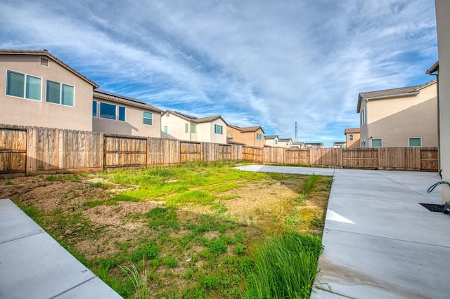 view of yard with a patio area, a fenced backyard, and a residential view