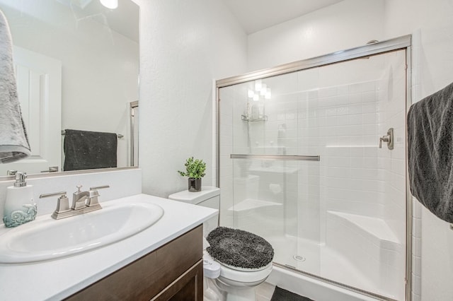 bathroom with toilet, a stall shower, and vanity