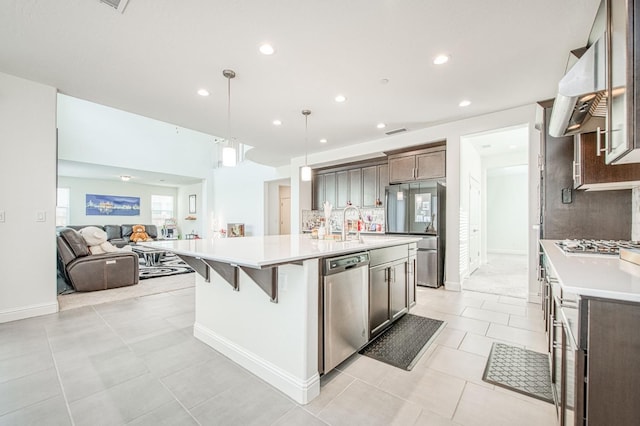 kitchen featuring appliances with stainless steel finishes, open floor plan, light countertops, backsplash, and exhaust hood