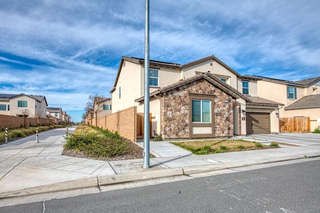 view of front of property featuring stone siding, fence, driveway, and stucco siding