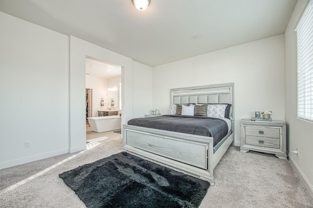 carpeted bedroom featuring baseboards and ensuite bathroom