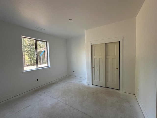 unfurnished bedroom featuring a closet, unfinished concrete flooring, and baseboards