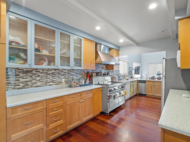 kitchen with light stone counters, decorative backsplash, appliances with stainless steel finishes, dark wood-type flooring, and wall chimney exhaust hood