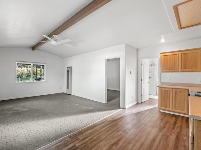 unfurnished living room with vaulted ceiling with beams, ceiling fan, dark wood finished floors, and baseboards