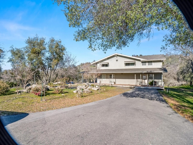 view of front of house with aphalt driveway, a front lawn, and a porch