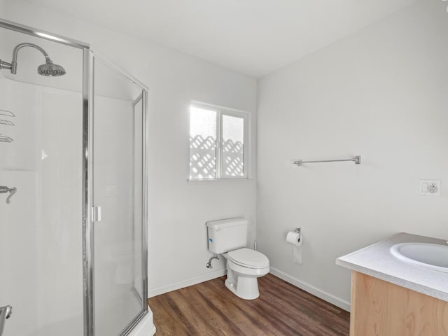 bathroom with baseboards, a shower stall, toilet, and wood finished floors