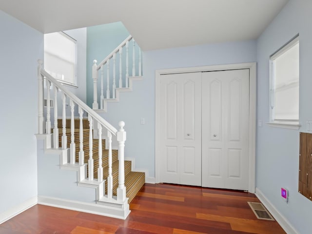 foyer featuring stairs, wood finished floors, visible vents, and baseboards