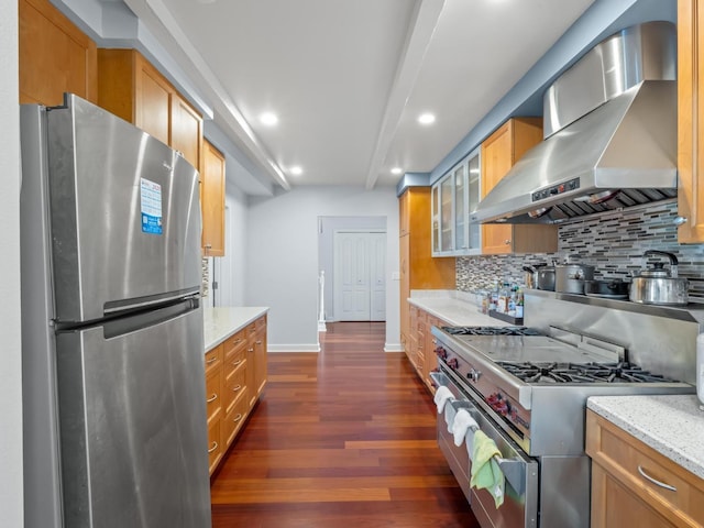 kitchen featuring appliances with stainless steel finishes, dark wood-type flooring, wall chimney range hood, and decorative backsplash