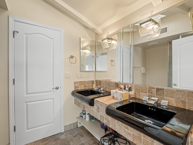 bathroom with tasteful backsplash, beam ceiling, and a sink