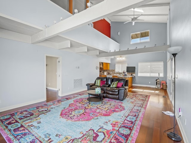 living area featuring visible vents, light wood-style flooring, beam ceiling, and a ceiling fan