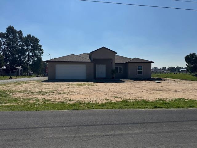 ranch-style home with dirt driveway and a garage