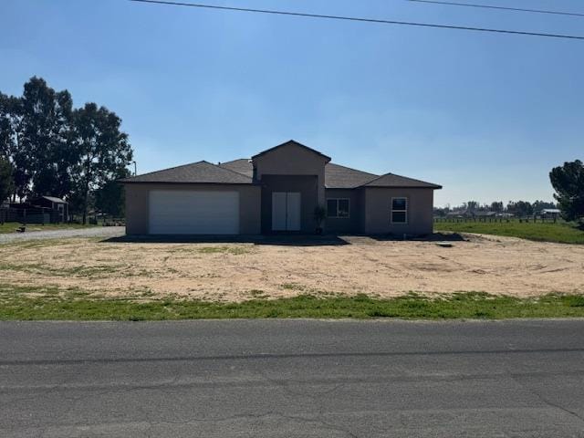 view of front facade featuring an attached garage and dirt driveway