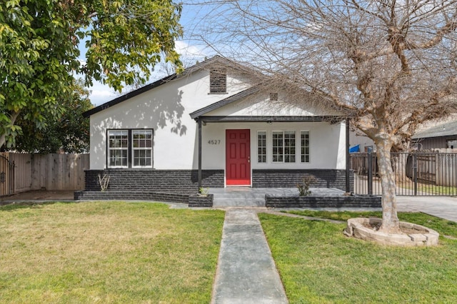 bungalow-style home featuring fence private yard, brick siding, a front lawn, and stucco siding