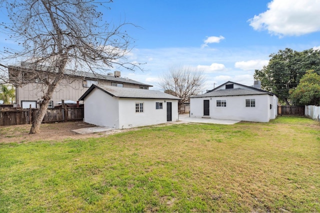 back of property with a patio, stucco siding, a lawn, a fenced backyard, and an outdoor structure