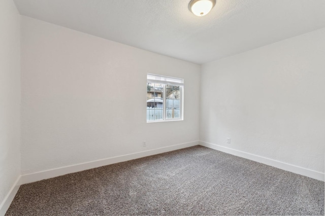 spare room featuring a textured ceiling, baseboards, and carpet flooring