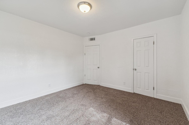 spare room with carpet, visible vents, and baseboards