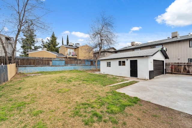 view of yard with a fenced backyard, a detached garage, and an outdoor structure