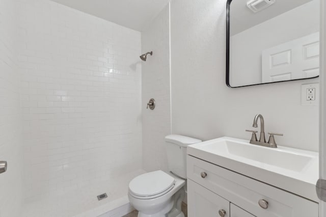 bathroom featuring visible vents, vanity, toilet, and tiled shower