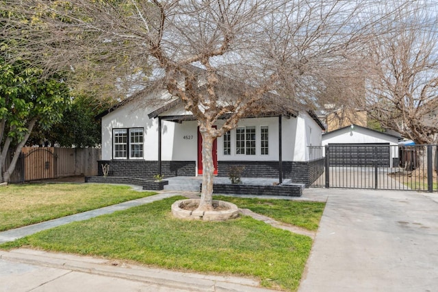 bungalow-style house featuring an outdoor structure, fence, a gate, stucco siding, and a front lawn