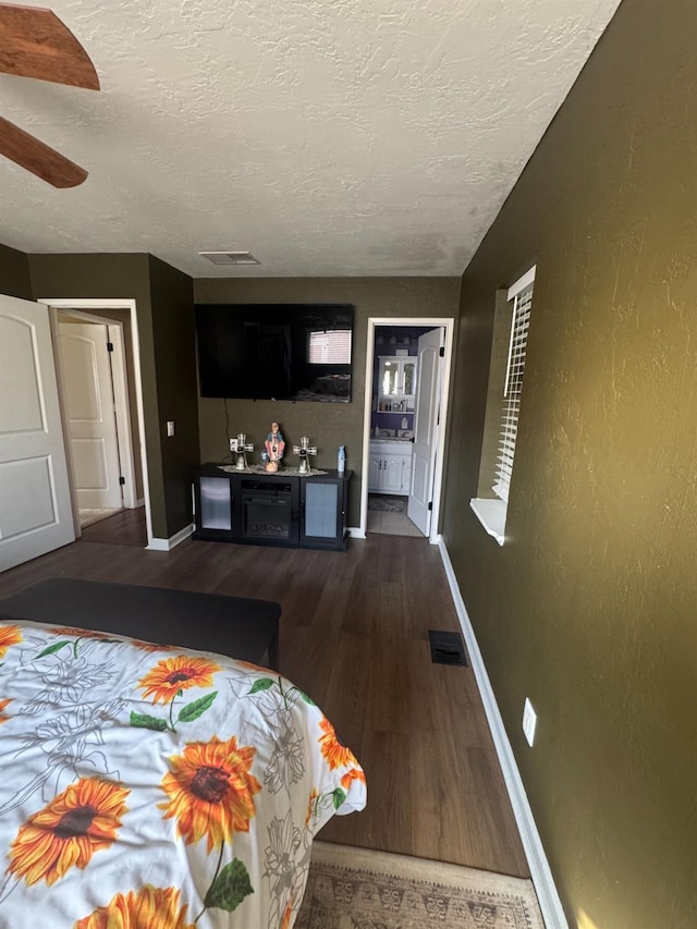 bedroom featuring visible vents, dark wood finished floors, a textured ceiling, and baseboards