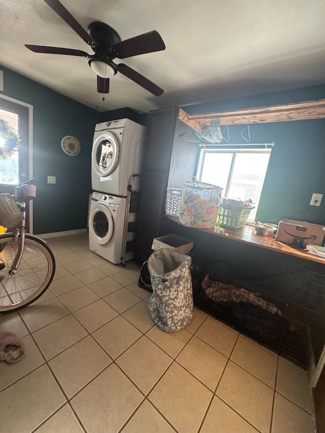 laundry room with laundry area, light tile patterned floors, baseboards, and stacked washer and clothes dryer