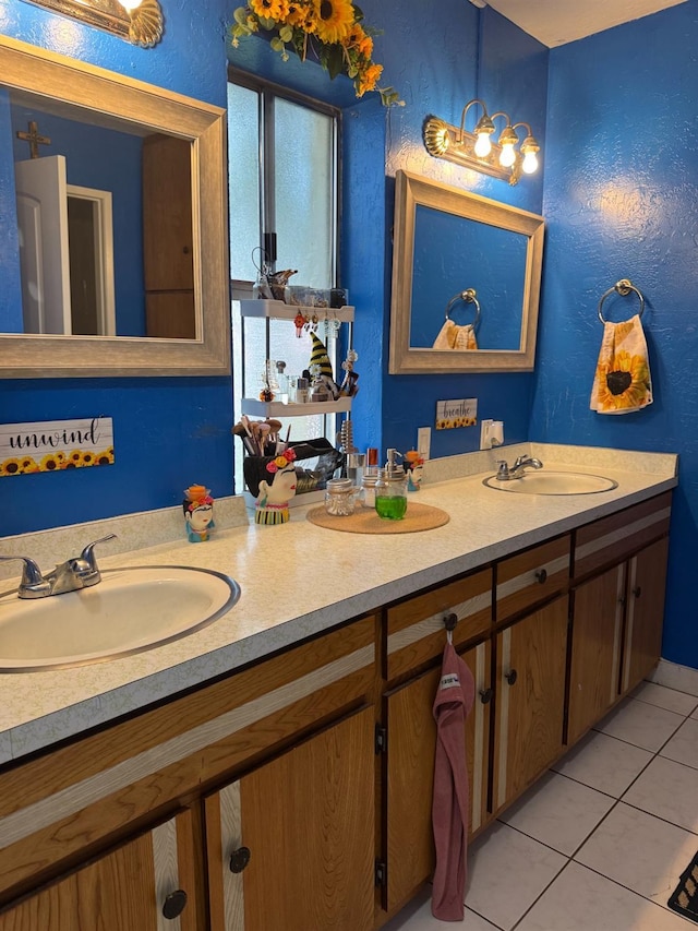 full bath with a textured wall, tile patterned flooring, a sink, and double vanity