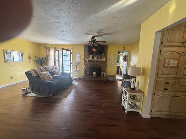 living area featuring a ceiling fan, a textured wall, wood finished floors, a textured ceiling, and a fireplace