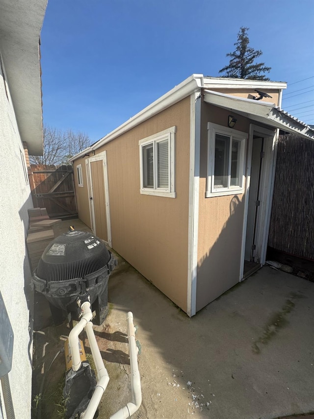 view of side of property with an outdoor structure, fence, and stucco siding