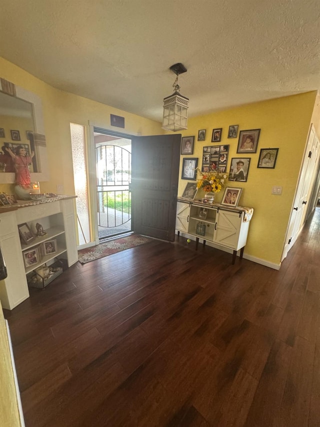 dining room featuring a textured ceiling, baseboards, and dark wood-style flooring