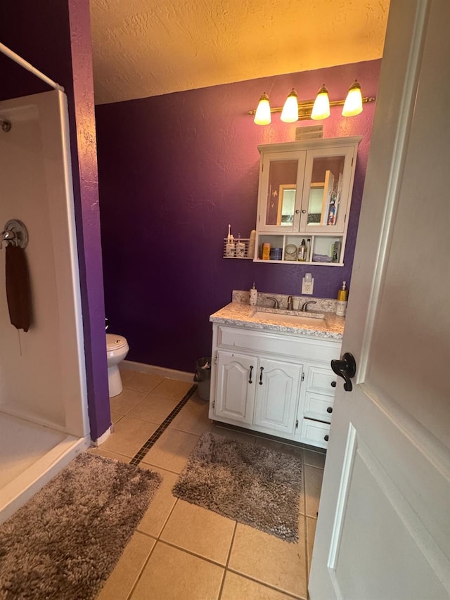 bathroom with a stall shower, vanity, baseboards, and tile patterned floors