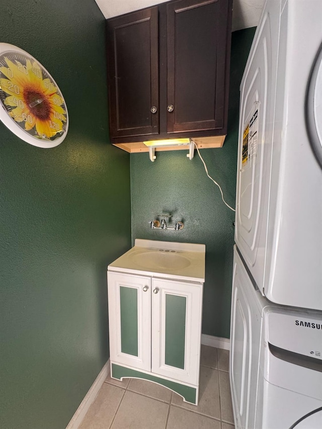 washroom with stacked washer and clothes dryer, cabinet space, baseboards, and light tile patterned flooring