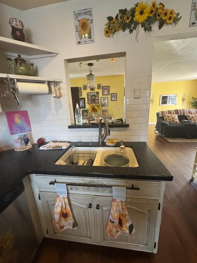 kitchen featuring dark countertops, stainless steel dishwasher, backsplash, and a sink