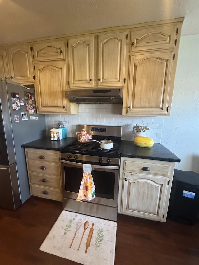 kitchen featuring dark wood finished floors, stainless steel appliances, dark countertops, decorative backsplash, and under cabinet range hood