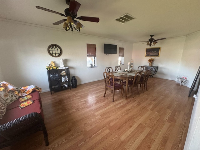 dining area featuring visible vents, ornamental molding, ceiling fan, wood finished floors, and baseboards