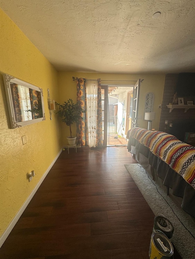 bedroom featuring access to outside, a textured ceiling, wood finished floors, and a textured wall