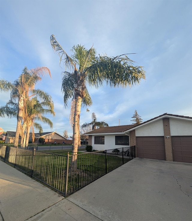 view of front of house with a fenced front yard, a garage, concrete driveway, stucco siding, and a front lawn