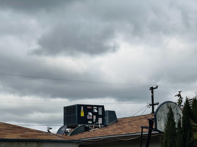 exterior details featuring a shingled roof and central air condition unit