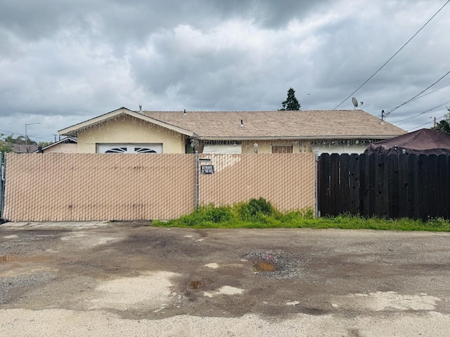 view of property exterior featuring a fenced front yard, a gate, roof with shingles, and stucco siding