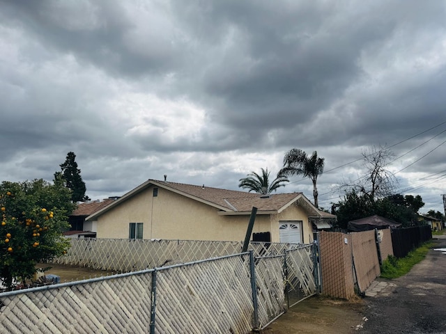 view of property exterior featuring fence, a gate, and stucco siding