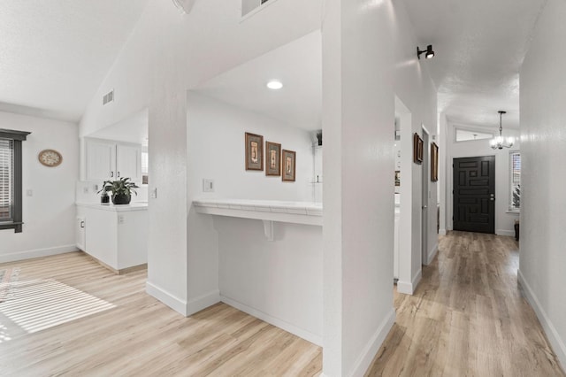 kitchen with vaulted ceiling, baseboards, visible vents, and light wood-style floors