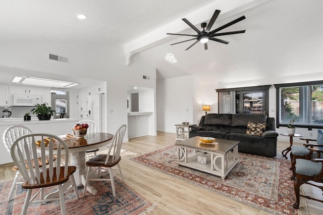 living area featuring beam ceiling, visible vents, light wood-style flooring, ceiling fan, and baseboards