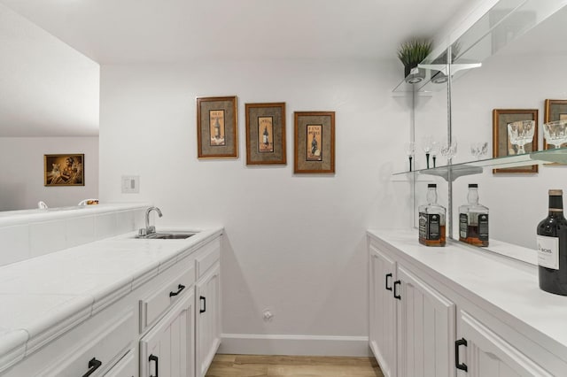 bathroom featuring wood finished floors, a sink, and baseboards