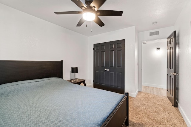 carpeted bedroom with a closet, visible vents, ceiling fan, and baseboards