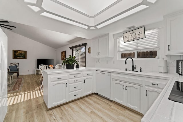 kitchen with dishwasher, a peninsula, a sink, and white cabinetry