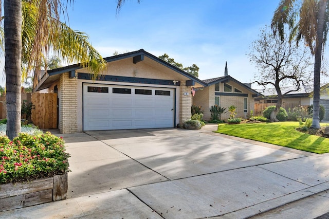 mid-century modern home featuring an attached garage, brick siding, fence, driveway, and a front yard