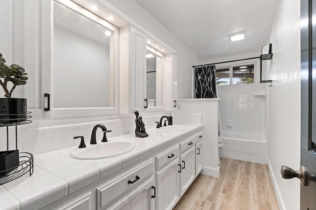 bathroom with toilet, double vanity, a sink, and wood finished floors