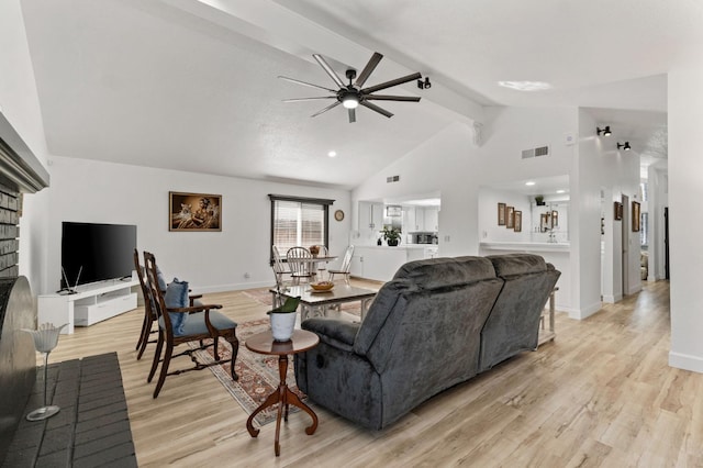 living room featuring vaulted ceiling with beams, a ceiling fan, baseboards, visible vents, and light wood-style floors