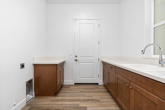 laundry area with hookup for an electric dryer, light wood-style flooring, cabinet space, and a sink