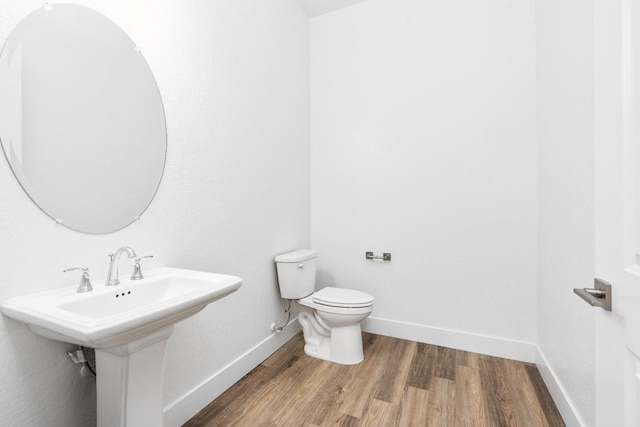 bathroom with baseboards, a sink, toilet, and wood finished floors