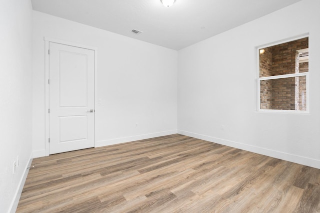 spare room featuring visible vents, light wood-style flooring, and baseboards